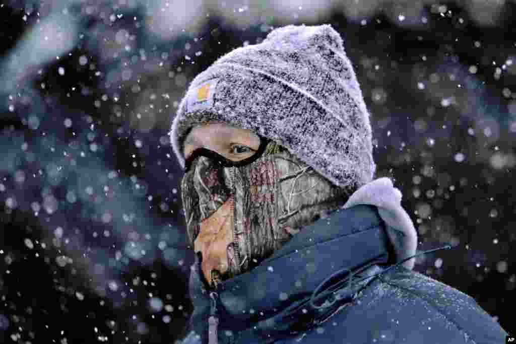 A man wears a face mask and heavy clothes while walking through downtown Springfield, Illinois, USA, in blowing and falling snow as a strong winter storm moves through the Midwest, Jan. 5, 2014. Temperatures not seen in years are likely to set records in the coming days across the Midwest, Northeast and South, creating dangerous travel conditions and prompting church and school closures.