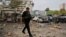A police officer walks past the burnt cars of a humanitarian aid organization at the site of a Russian missile strike on an office building, amid the Russia-Ukraine conflict, in Kyiv, Ukraine, Sept. 2, 2024.