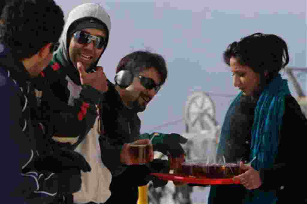 An Iranian woman offers tea to her friends as they spend leisure time in the Tochal mountain area north of Tehran, Iran on Friday Dec. 19, 2008. All women must wear a veil in public places in Iran according to Islamic rules but the mountain is the only pl