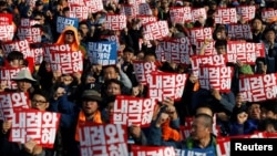 People chant slogans at a rally calling for President Park Geun-hye to step down in central Seoul, South Korea, Nov. 12, 2016. The placards read, "Step down Park Geun-hye."