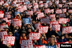 People chant slogans at a rally calling for President Park Geun-hye to step down in central Seoul, South Korea, Nov. 12, 2016. The placards read, "Step down Park Geun-hye."