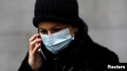 A woman in a surgical mask uses her cellphone after more cases of coronavirus were confirmed in Manhattan, New York City, New York, U.S., March 11, 2020. REUTERS/Andrew Kelly