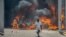 Seorang anak laki-laki berlari menjauh dari sebuah dealer mobil yang dibakar para pengunjuk rasa di Port-au-Prince, Haiti, 17 Maret 2021. 