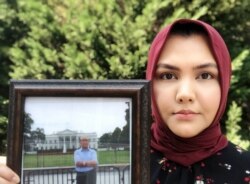 FILE - Subi Mamat Yuksel holds a photo of her father, Mamat Abdulla, in Virginia in April. (Photo courtesy: Subi Mamat Yuksel)