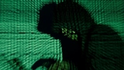 A man holds a laptop computer as cyber code is projected on him in this illustration picture taken on May 13, 2017. 