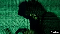 A man holds a laptop computer as cyber code is projected on him in this illustration picture taken on May 13, 2017. 