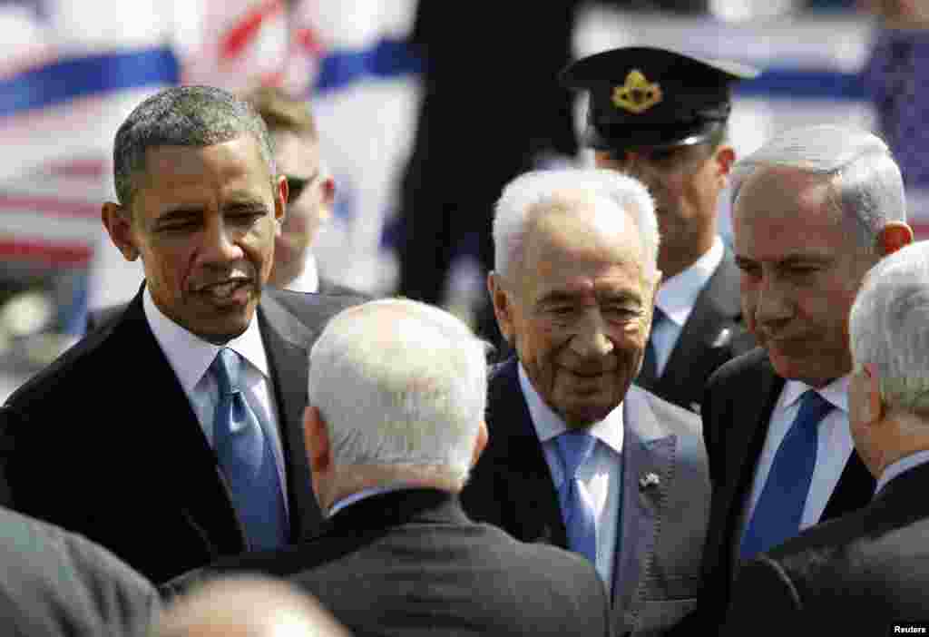 U.S. President Barack Obama, Israeli President Shimon Peres and Israeli Prime Minister Benjamin Netanyahu speak with greeters at Ben Gurion International Airport in Tel Aviv, March 20, 2013.