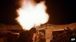 Russian soldiers protect their ears as they fire a mortar against a suspected rebel base near the Chechen village of Samashki, 30 kilometers (20 miles) west of Grozny, Chechnya, Russia, Aug. 10, 2000. 