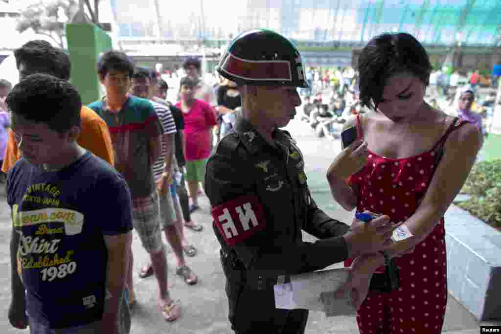 Seorang tentara menuliskan angka di tangan Thanompong, seorang transgender berusia 21 tahun, dalam acara militer yang diadakan di sebuah sekolah di Klong Toey, wilayah kumuh dermaga di Bangkok, Thailand.