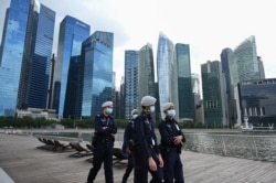 FILE - Police officers walk on patrol along the Marina Bay promenade in Singapore, Dec. 27, 2020.