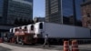 Seorang pekerja melewati truk-truk berpendingin untuk menyimpan jenazah pasien virus corona (COVID-19), di Manhattan, Kota New York, 26 Maret 2020. (Foto: Reuters)