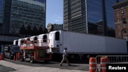 Seorang pekerja melewati truk-truk berpendingin untuk menyimpan jenazah pasien virus corona (COVID-19), di Manhattan, Kota New York, 26 Maret 2020. (Foto: Reuters)