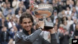 Petenis Spanyol, Rafael Nadal memegang trophy juara Perancis Terbuka untuk yang ke-7 kalinya setelah mengalahkan Novak Djokovic (11/6).