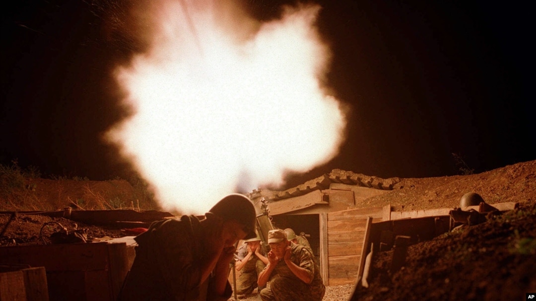 Russian soldiers protect their ears as they fire a mortar against a suspected rebel base near the Chechen village of Samashki, 30 kilometers (20 miles) west of Grozny, Chechnya, Russia, Aug. 10, 2000. 