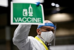 Doctor John Thayer holds up a sign to signal his station needs more vaccine doses in a coronavirus disease (COVID-19) vaccination site at Lumen Field Event Center in Seattle, Washington, March 13, 2021.