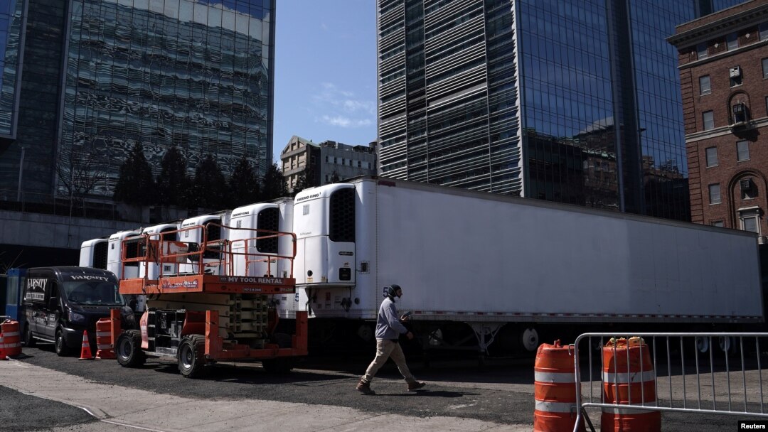 Seorang pekerja melewati truk-truk berpendingin untuk menyimpan jenazah pasien virus corona (COVID-19), di Manhattan, Kota New York, 26 Maret 2020. (Foto: Reuters)