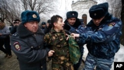 Volgograd kentinde izinsiz gösteri yapan kişilerden birini polisler götürürken