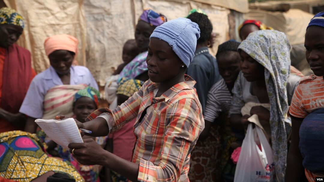Blessing John, who escaped from Boko Haram, hands out used clothes to internally displaced people at the Sabon Kuchigora refugee settlement on the outskirts of Abuja, Dec. 17. (Chris Stein/VOA)