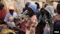 Blessing John, who escaped from Boko Haram, hands out used clothes to internally displaced people at the Sabon Kuchigora refugee settlement on the outskirts of Abuja, Dec. 17. (Chris Stein/VOA)