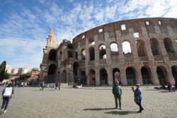 People walk by the Colosseum in Rome, March 5, 2020. Italy has closed all schools and universities and barred fans from all sporting events for the next few weeks.