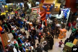 FILE - Customers wait in line to make their purchases at the Times Square Toys R Us, New York, Nov. 28, 2013. The one-time flagship store, a huge tourist destination, was closed about two years ago.