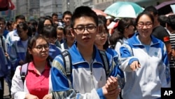 A high school student holds his hand as he and others leave a school after finishing their college entrance exam in Beijing, Wednesday, June 7, 2017.