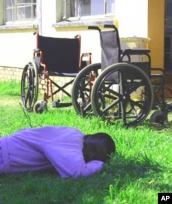 A patient who’s become disabled because of TB sleeps on the grass outside a ward at Zithulele Hospital