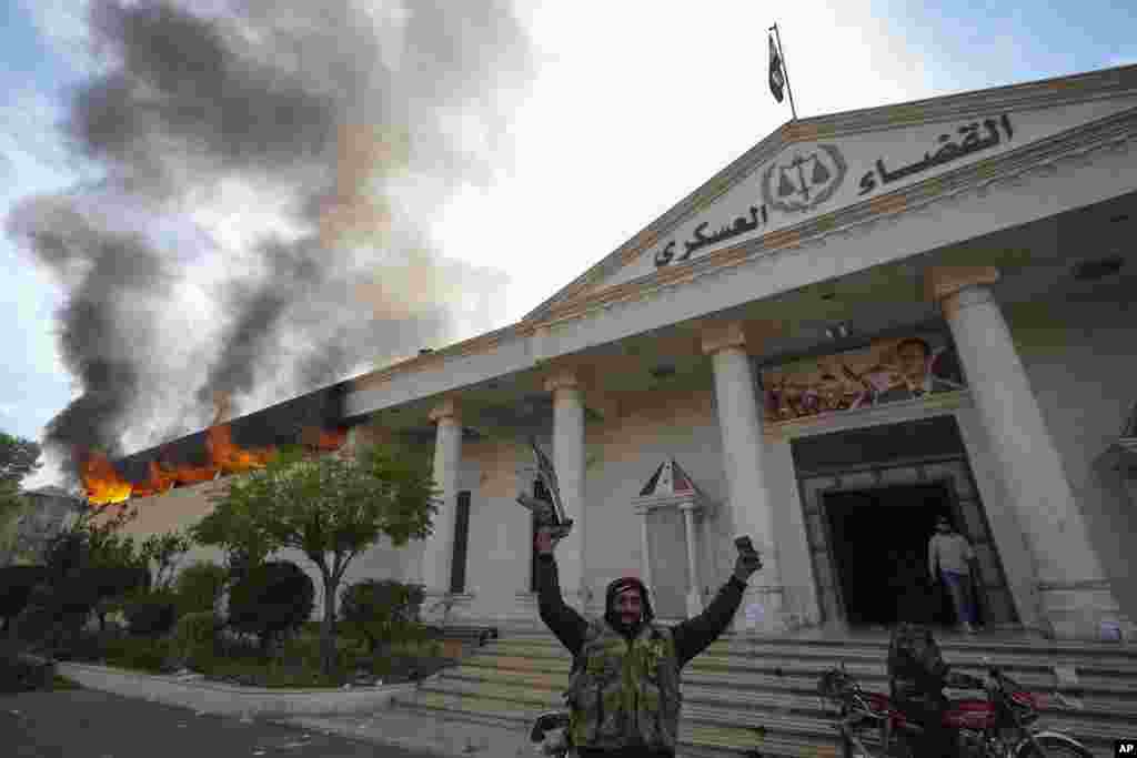 Opposition fighters celebrate as they burn down a military court in Damascus, Syria.