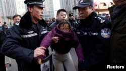Liu Chunxia, a supporter of Xu Zhiyong, is detained by policemen while she gathers with other supporters near a court.