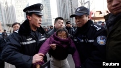 Liu Chunxia, a supporter of Xu Zhiyong, one of China's most prominent rights advocates, is detained by policemen while she gathers with other supporters nearby a court where Xu's trial is being held in Beijing, Jan. 22, 2014.
