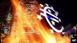 In this photo taken with a fisheye lens, flames from a fire set alight in a container by activists of the Frankfurt Occupy movement are seen in front of the European Central Bank and a sculpture of the euro symbol in Frankfurt, Germany, November 21, 2011 