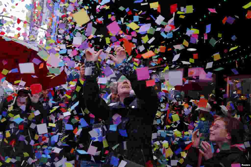 Pedestrians stop to watch confetti fall as members of the Times Square Alliance perform an &quot;air worthiness test&quot; for the confetti that is similar to what will be used for New Year&#39;s Eve in New York.