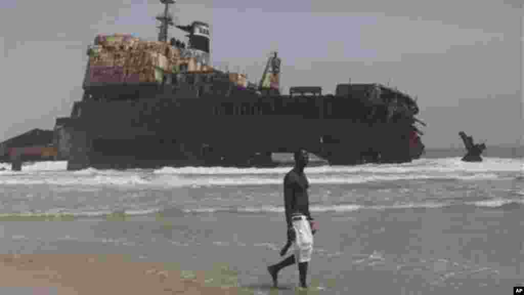 A man walks past the rusting hulk of an abandoned ship beached on the coastline in Nigeria.