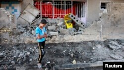 A youth stands at the site of a car bomb attack in Baghdad, a day after the bombing, Aug. 29, 2013.