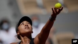 Petenis Jepang Naomi Osaka mengoper bola ke Patricia Maria Tig dari Rumania selama kemenangan putaran pertama Osaka di turnamen tenis terbuka Prancis di stadion Roland Garros pada 30 Mei 2021, di Paris. (Foto: AP)