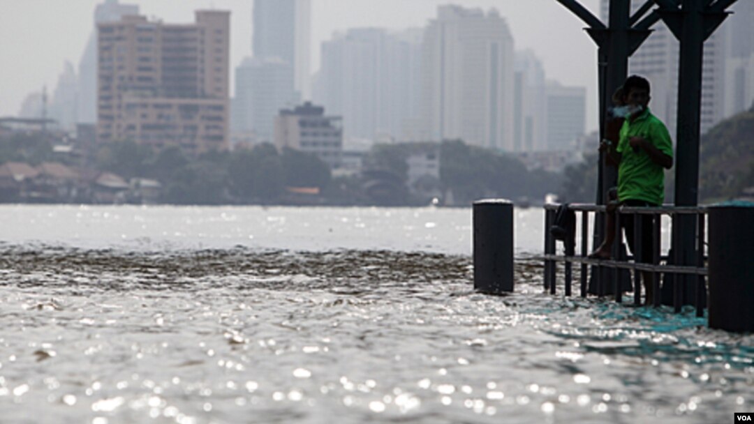 Seorang warga Thailand berdiri di dekat jembatan yang tergenang air di sungai Chao Praya, Bangkok (14/10).