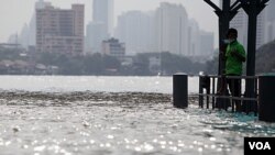 Seorang warga Thailand berdiri di dekat jembatan yang tergenang air di sungai Chao Praya, Bangkok (14/10).