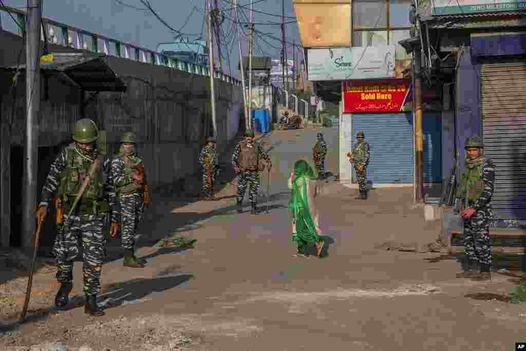 A Kashmiri woman covers her face as she walks past paramilitary soldiers standing guard in a closed market area in Srinagar, Indian controlled Kashmir. Indian officials are limiting public movement after the death Thursday of a top separatist leader.