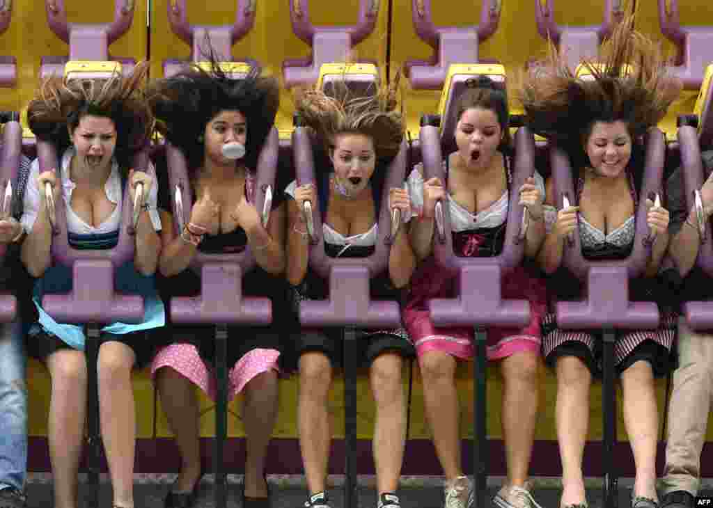 Young women in traditional Bavarian Dirndl dresses enjoy a fun ride during the Oktoberfest beer festival at the Theresienwiese fair grounds in Munich, southern Germany, on the fair&#39;s opening day.