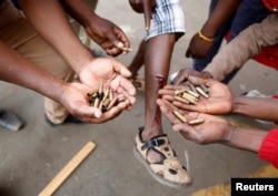 FILE: Opposition Movement for Democratic Change supporters hold spent rounds and show injuries after soldiers opened fire outside the party's headquarters in Harare, Zimbabwe, Aug. 1, 2018.