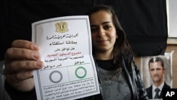 A Syrian woman displays her ballot at a polling station during a referendum on the new constitution, in Damascus, Syria, Sunday, February 26, 2012.