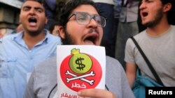 Egyptian protesters hold placards with the Arabic inscription reading ‘danger’ and shout slogans as they demonstrate against the International Monetary Fund (IMF) delegation visit in Cairo, April 3, 2013.