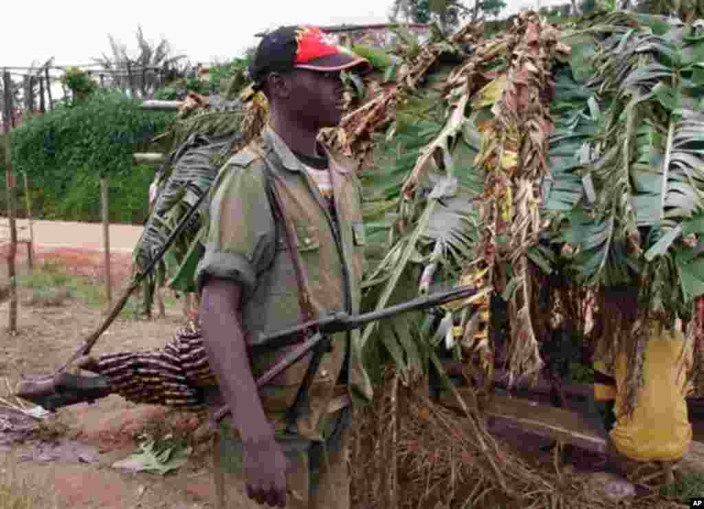 An unidentified Rwandan rebel carries a machine gun some 20 kilometers from the town of Masisi, Democratic Republic of Congo on Friday, Nov. 4, 2005. The Rwandans shopping in a Congolese market say they want to live peacefully alongside Congolese villager