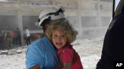 Un casque blanc, Défense civile syrienne, secourant un enfant après un raid aérien, province de Deraa, en Syrie, le 14 juin 2017.