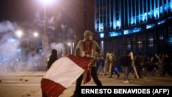 Un manifestant, partisan du président péruvien évincé Martin Vizcarra, tient un drapeau péruvien lors des affrontements après une manifestation contre le gouvernement du président intérimaire Manuel Merino à Lima le 14 novembre 2020.