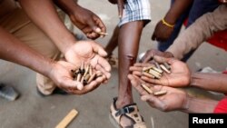 FILE: Opposition Movement for Democratic Change supporters hold spent rounds and show injuries after soldiers opened fire outside the party's headquarters in Harare, Zimbabwe, Aug. 1, 2018.