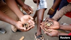 Opposition Movement for Democratic Change supporters hold spent rounds and show injuries after soldiers opened fire outside the party's headquarters in Harare, Zimbabwe, Aug. 1, 2018.