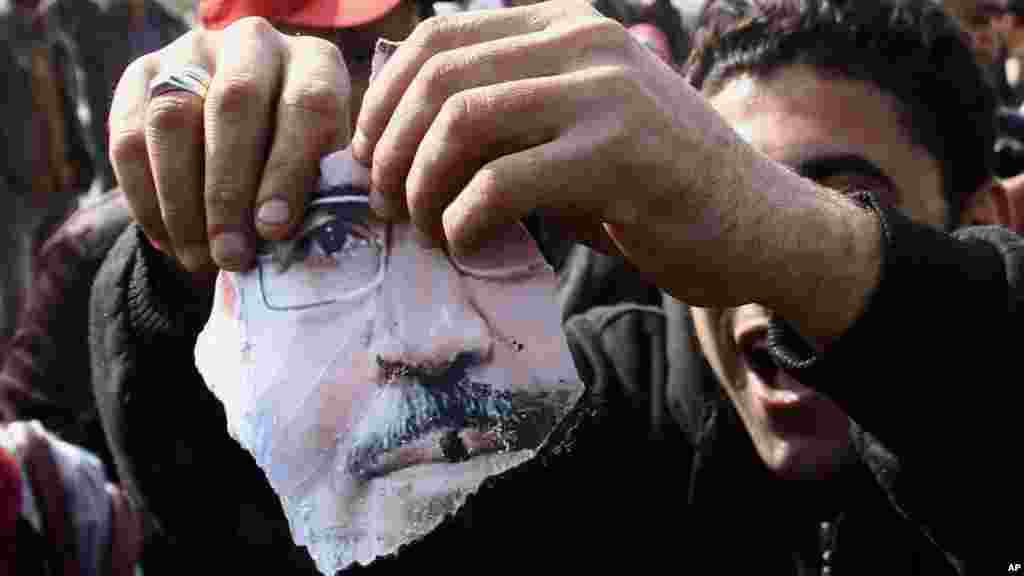 A man holds a part of a torn poster showing Egypt's ousted President Mohamed Morsi during clashes in Cairo, Jan. 8, 2014.
