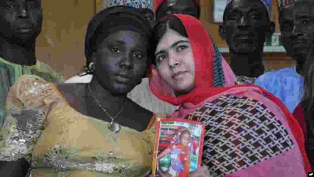 La défenseuse pakistanaise de l&rsquo;éducation pour jeunes filles, Malala Yousafzai, tient la photo d&rsquo;une écolière enlevée, Sarah Samuel, avec la mère de la victime, à Abudja, Nigeria, le 13 juillet 2014. (AP Photo/Olamikan Gbemiga) 