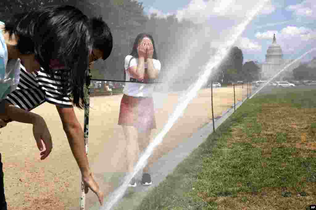 Students visiting from Xining, China react to the spray coming from large sprinklers watering the lawn of the National Mall as part of turf restoration efforts.